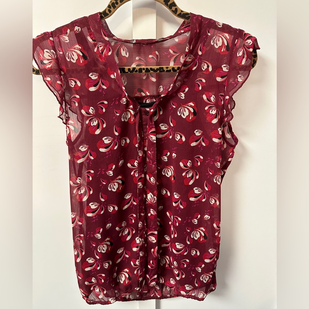 Burgundy/Red sleeveless floral blouse.